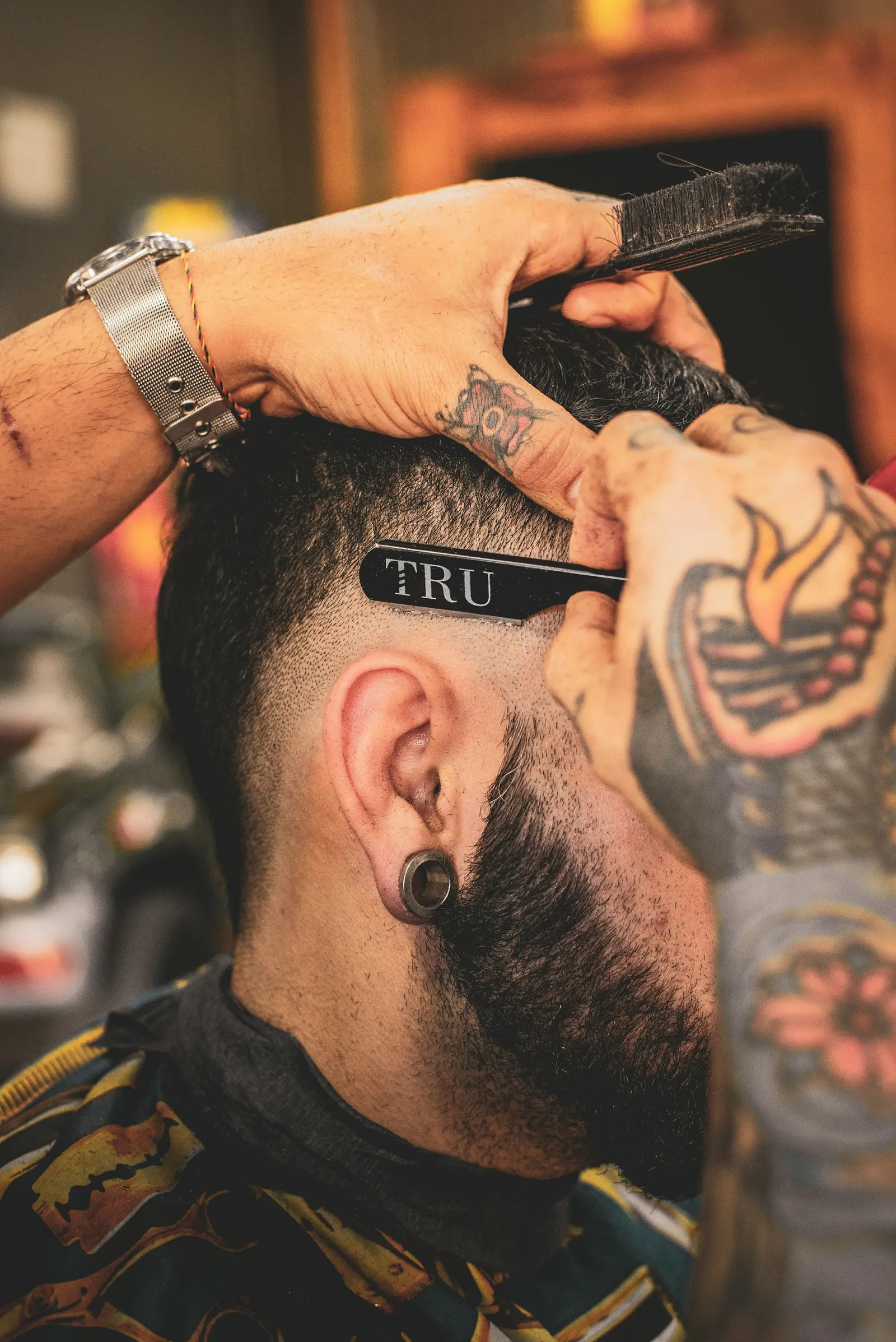 Barbero tatuado haciendo un corte con navaja