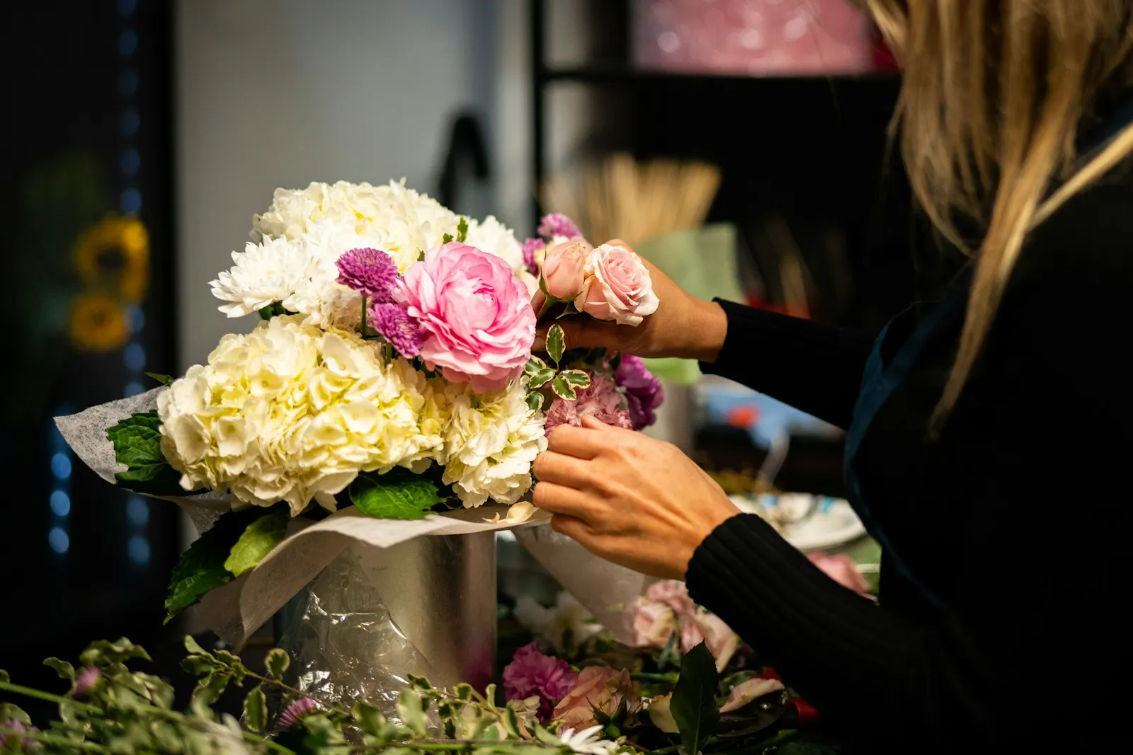 Florista armando un arreglo de rosas y hortensias
