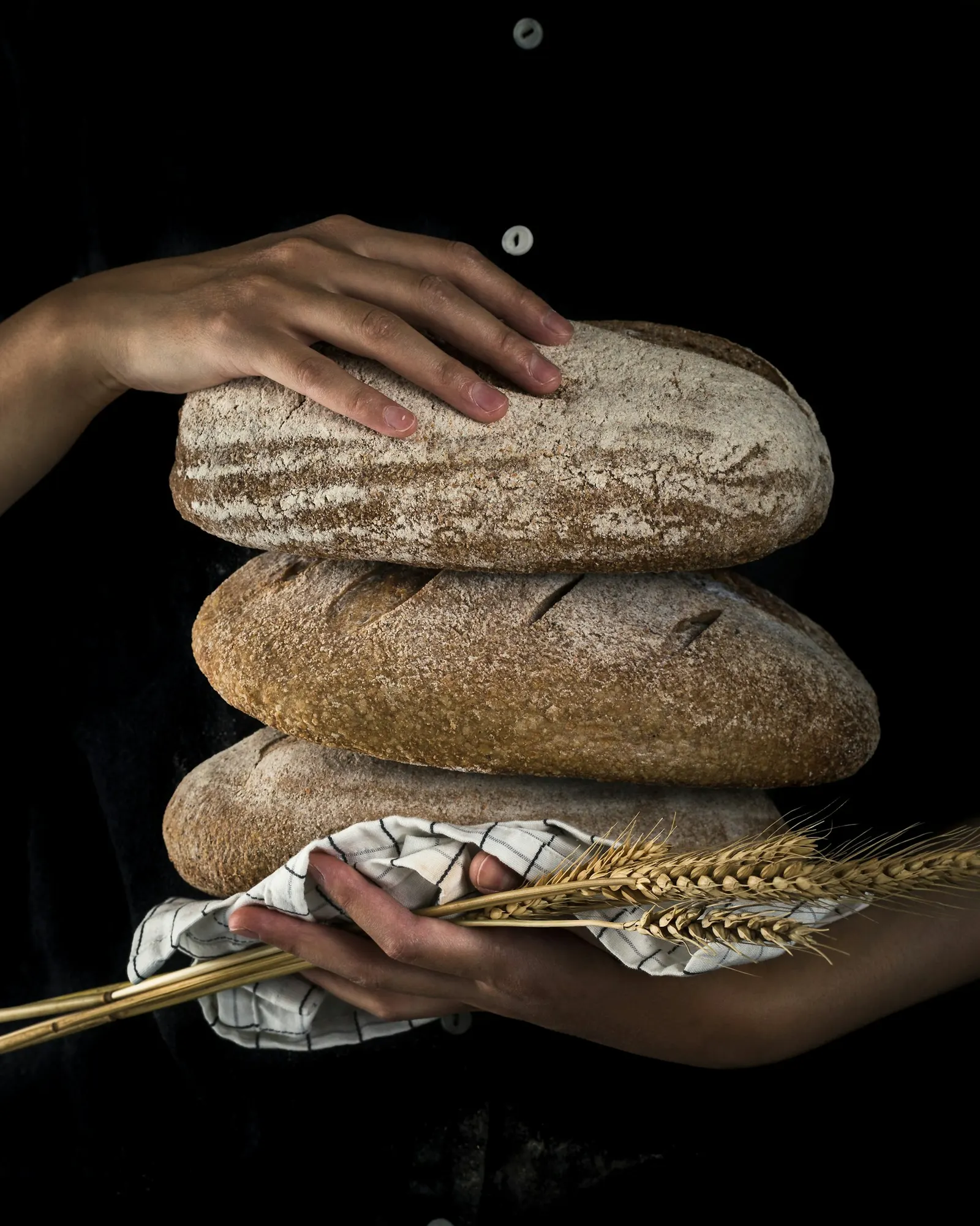 Manos sosteniendo hogazas de pan artesanal