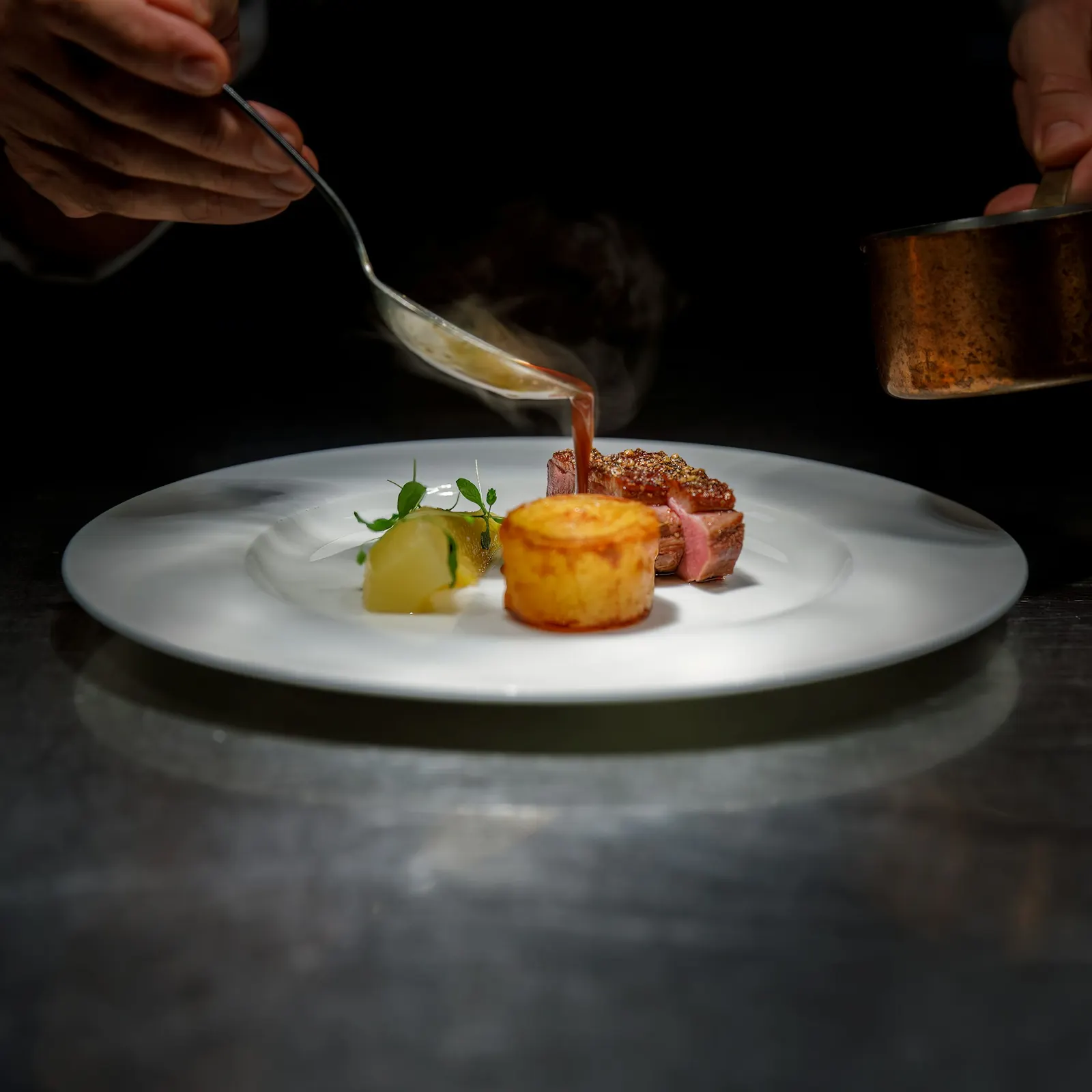 Chef sirviendo salsa sobre un platillo emplatado