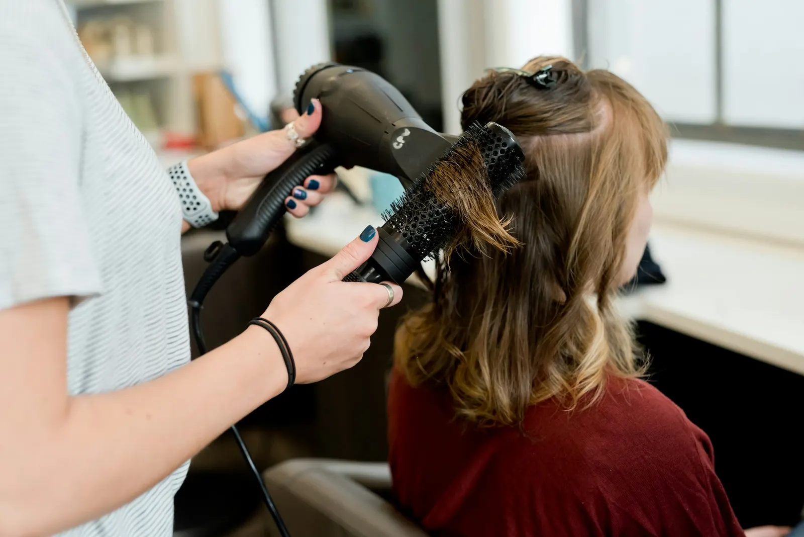 Estilista secando el cabello de una clienta